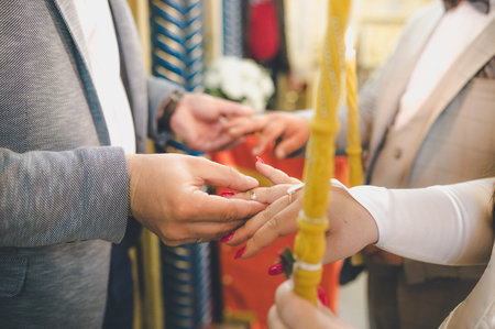 A Christian wedding ceremony with the godfather swapping wedding rings on hands of bride and groomの写真素材