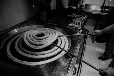 A grayscale closeup shot of a delicious fresh churro spiral being friedの写真素材