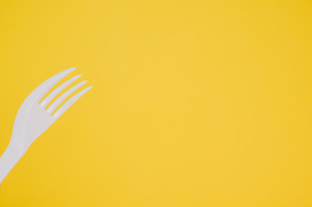 A closeup shot of a plastic fork on a yellow background