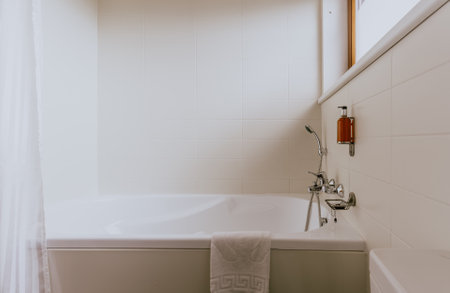 A white bathroom with a towel on the bathtubの写真素材