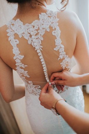 A bridesmaid helping put on a wedding dress on the brideの写真素材