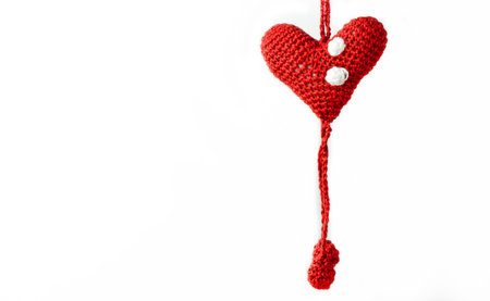 A closeup shot of amigurumi heart pattern hanging on white backgroundの写真素材