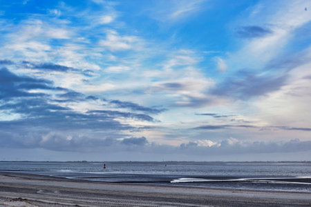 A breathtaking view of a sandy beach and cloudy sky at sunsetの写真素材