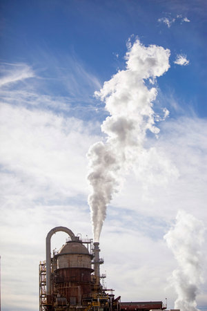 A vertical shot of a smoking industry under a blue cloudy sky