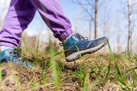 A selective focus of a hiker's shoes on a grassy field