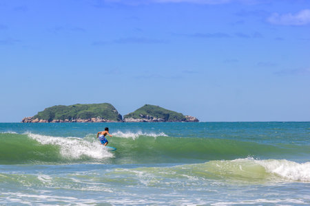A boy surfing in the sea with an island in the backgroundの写真素材