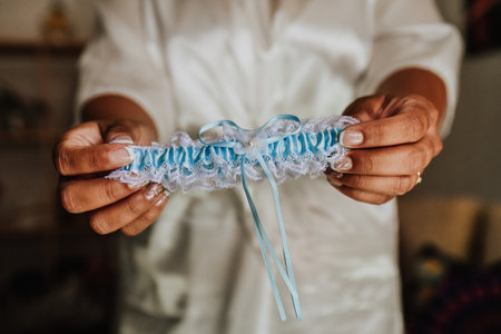 A closeup of a person holding a wedding bride garter under the lights with a blurry backgroundの写真素材
