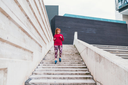 A closeup shot of a sporty red-haired Caucasian female doing exercises outdoorの写真素材