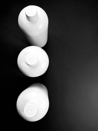 A top view of white plastic bottles isolated on a black surfaceの写真素材