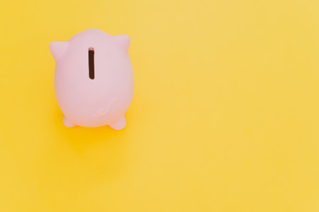 A top view of a pink piggy bank isolated on a yellow backgroundの写真素材