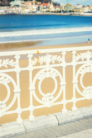 A vertical shot of a white fence near the La Concha beach in Spainの写真素材