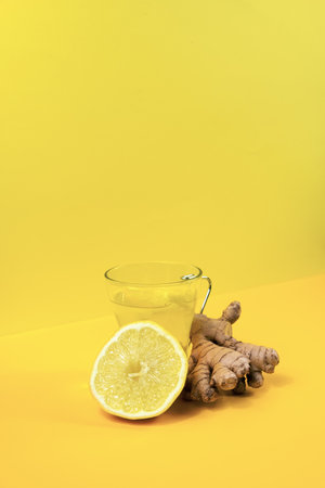 A vertical shot of a cup of ginger and lemon tea with ingredients isolated on a yellow backgroundの写真素材
