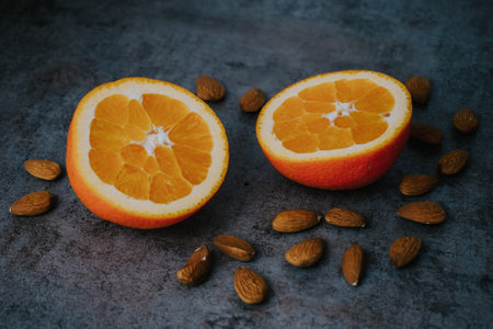 a closeup of sliced oranges and almond nuts on a gray surfaceの写真素材