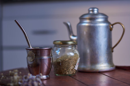 A closeup shot of a traditional silver teapot, a cup, and herbal teaの写真素材