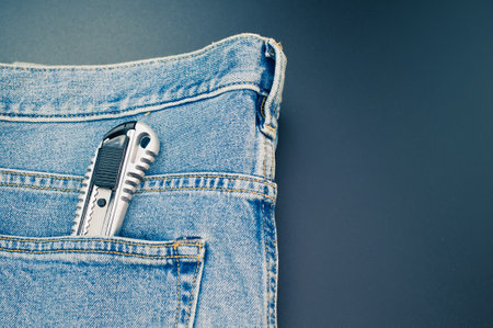 A closeup shot of a pocket knife in the jeans pocket on a blue backgroundの写真素材