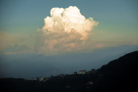 A beautiful mixture of white and gray clouds above a town on vast hills before sunsetの写真素材