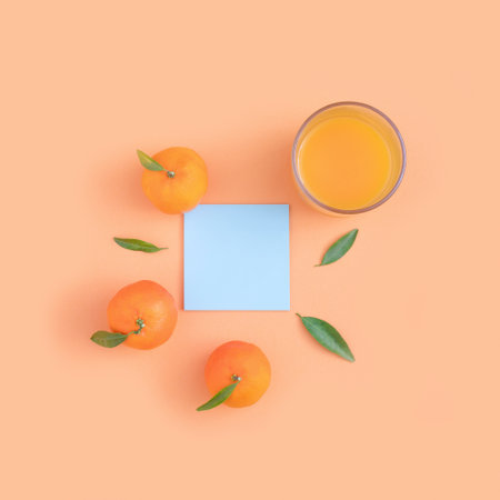 An overhead shot of oranges and a glass of juice on pastel orange backgroundの写真素材