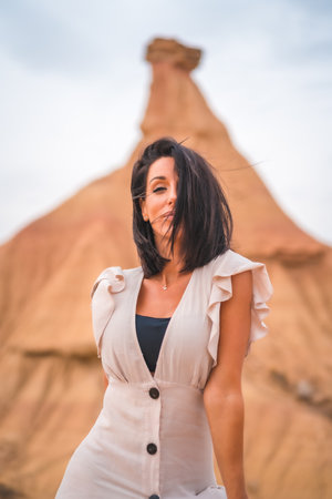 A sensual gazes from a brunette Caucasian girl in an explorer outfit with a white dress in a desert on a cloudy afternoonの写真素材