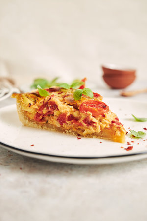 A vertical shot of a delicious Francaise quiche piece on a white table with ingredients