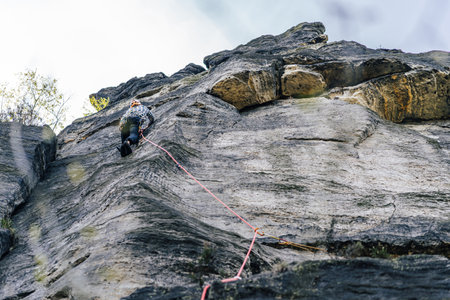 A rock climber on a high cliff. Climbing on sandstone, epic extreme sport photo. Trad climber on czech sandstone, Czech republicの写真素材