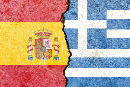 The flags of Spain and Greece  painted on cracked wall backgroundの写真素材