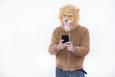 A man with a roaring lion full mask using his phone isolated on white backgroundの写真素材