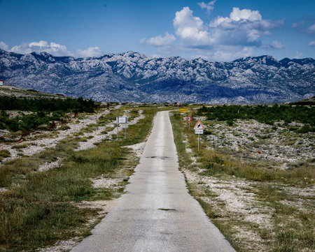 A beautiful view of a road surrounded by rocky mountains under a cloudy skyの写真素材