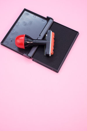A vertical shot of black ink pad with stamp isolated on pink backgroundの写真素材