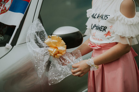 A young lady fixing a wedding decoration attached to a car light