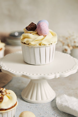 A delicious carrot cupcake with whipped cream and topping from candies in eggs shape for Easter