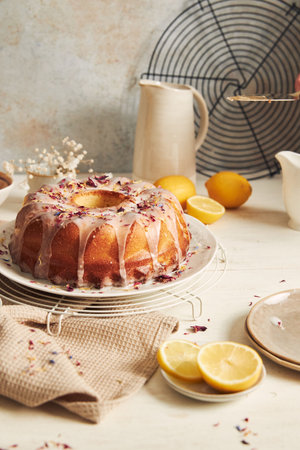 A vertical shot of a delicious citron cake with a cut piece with glaze and flower on top on a tableの写真素材