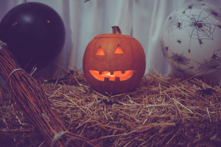 A closeup shot of a broom and a carved pumpkin for Halloween decorationsの写真素材