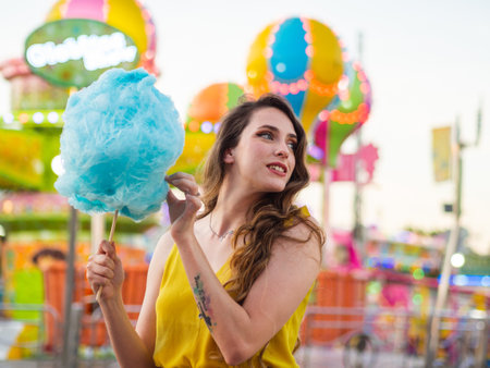 An attractive Caucasian female posing with blue cotton candy at a carnivalの写真素材