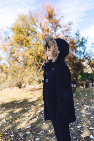 A portrait of a little Caucasian girl in the park in wintertime on a blurred backgroundの写真素材
