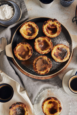 A closeup shot of delicious Pastel de Nata Vanilla pastries with espresso on a white table