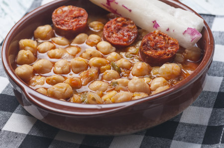 A closeup of chickpeas stew with chorizo and radishes on a bowlの写真素材