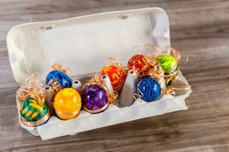 A bunch of cute and funny easter eggs in an egg box on wooden background