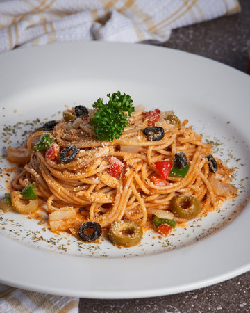 A closeup shot of delicious pasta with olives on a white plateの写真素材
