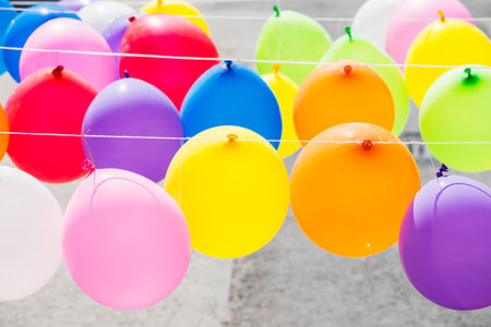 The different colored balloons hanging on the ropes outside.の写真素材