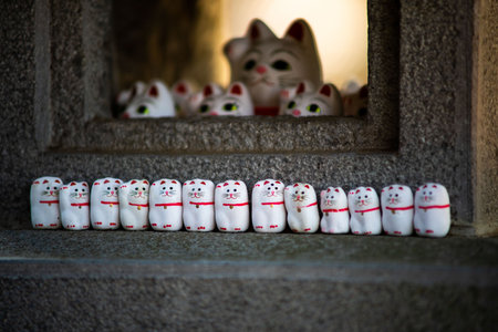 A soft focus of a row of beckoning cat sculptures on a concrete surfaceの写真素材