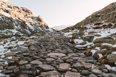 Beautiful scenery with a stony pathway through the hills covered in snow