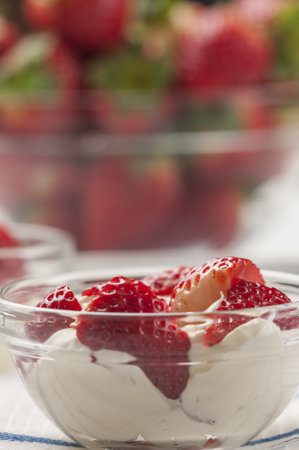 A selective focus shot of strawberries with cream in a small glass bowlの写真素材