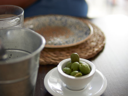A selective focus of green olives on a small white bowl and saucerの写真素材