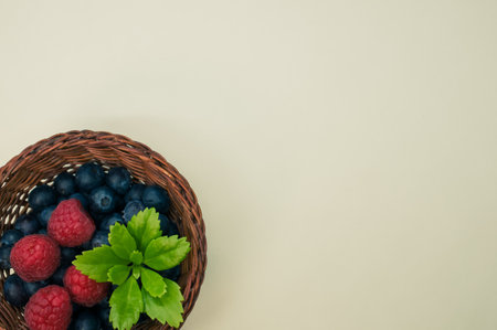 A top view of blueberries raspberries and leaves in a basketの写真素材