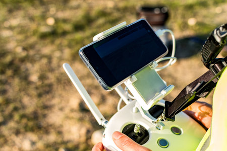 A shallow focus of male hands holding a remote controller of a drone on blurred background of a...