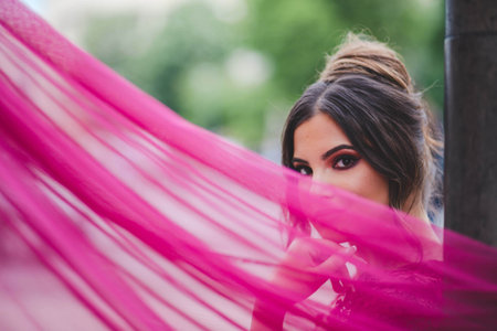 A shallow focus shot of a young beautiful Caucasian female in a pink dress posing at cameraの写真素材