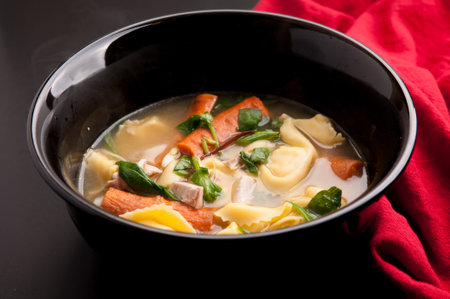 rich pasta tortellini soup with chicken and fresh vegetablesの写真素材