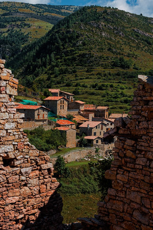 A vertical shot of stone houses built on a hillside captured from a huge wall crack