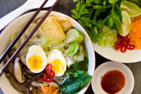 A high angle shot of ramen with egg and side dish on a tableの写真素材