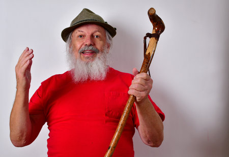 An elderly Caucasian male holding up a beautifully shaped wooden caneの写真素材